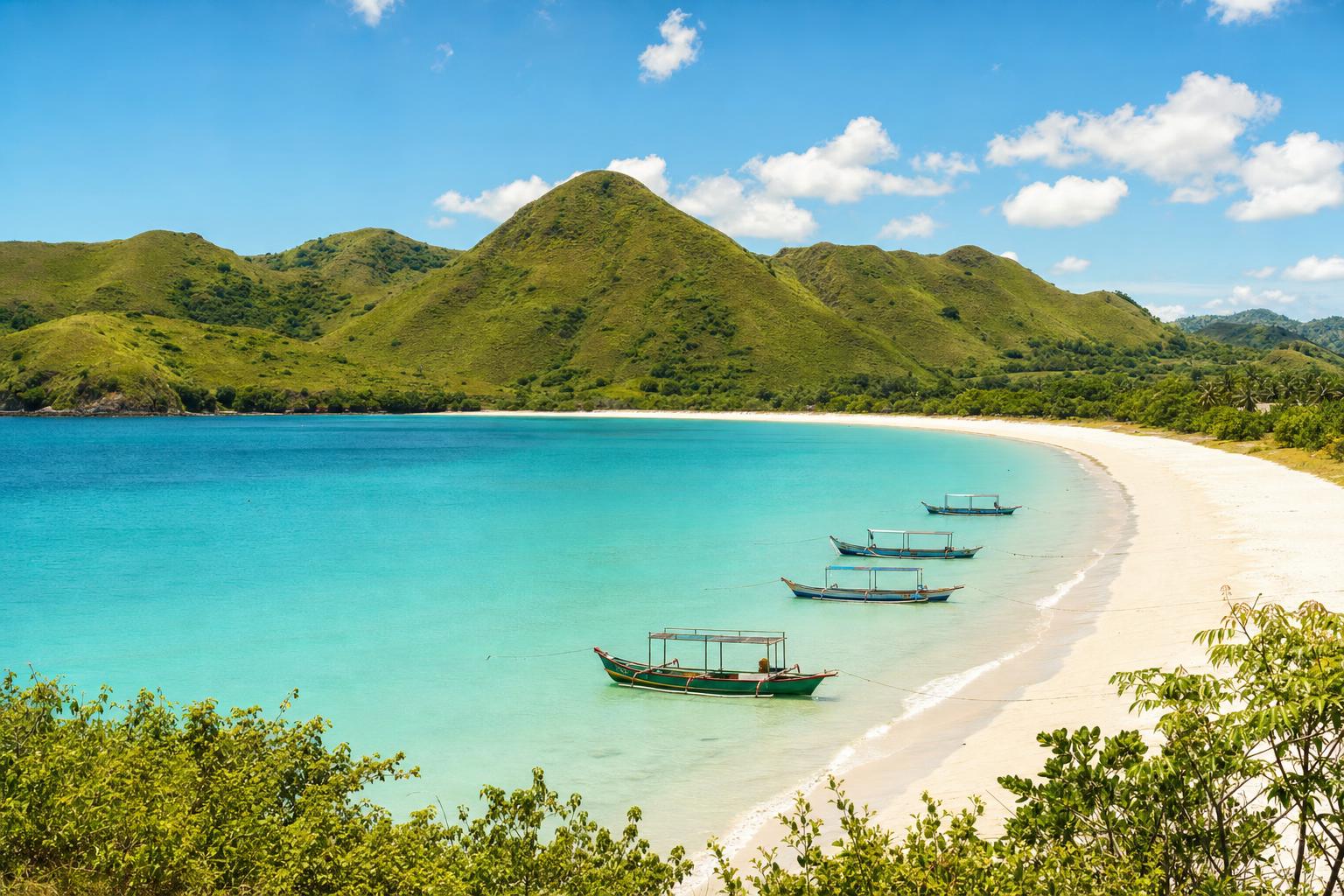 Turquoise horseshoe bay with fishing boats and green hills on Lombok's south coast
