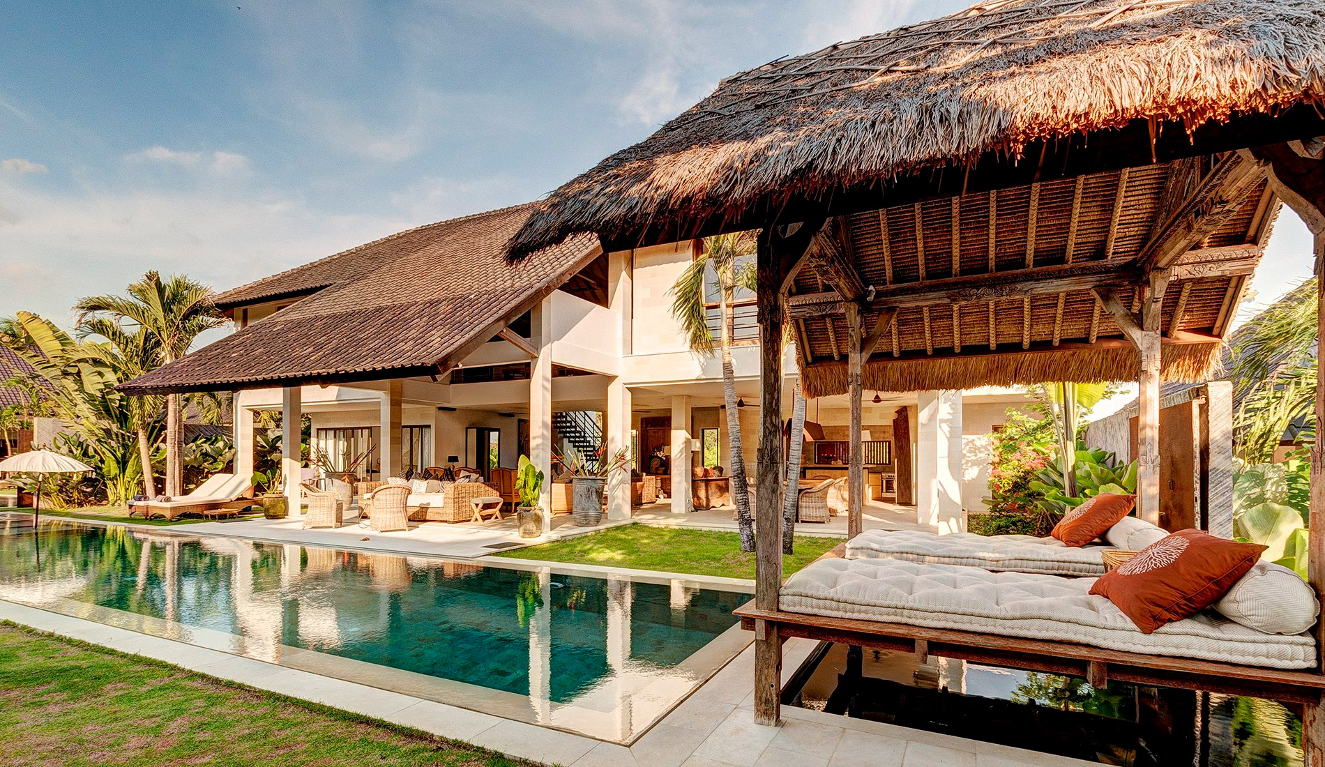 Thatched poolside bale beside a villa and swimming pool at golden hour at Abaca Villas, Petitenget, Seminyak