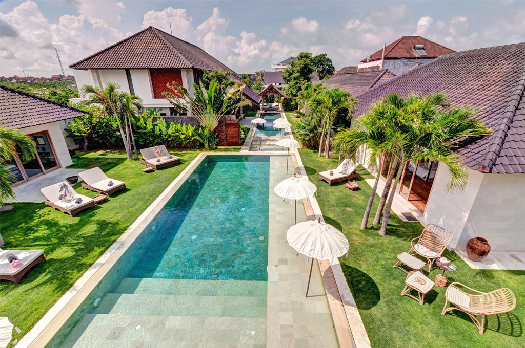 Long pool, sun loungers and garden framed by the villa roofs at Abaca Villas, Petitenget, Seminyak