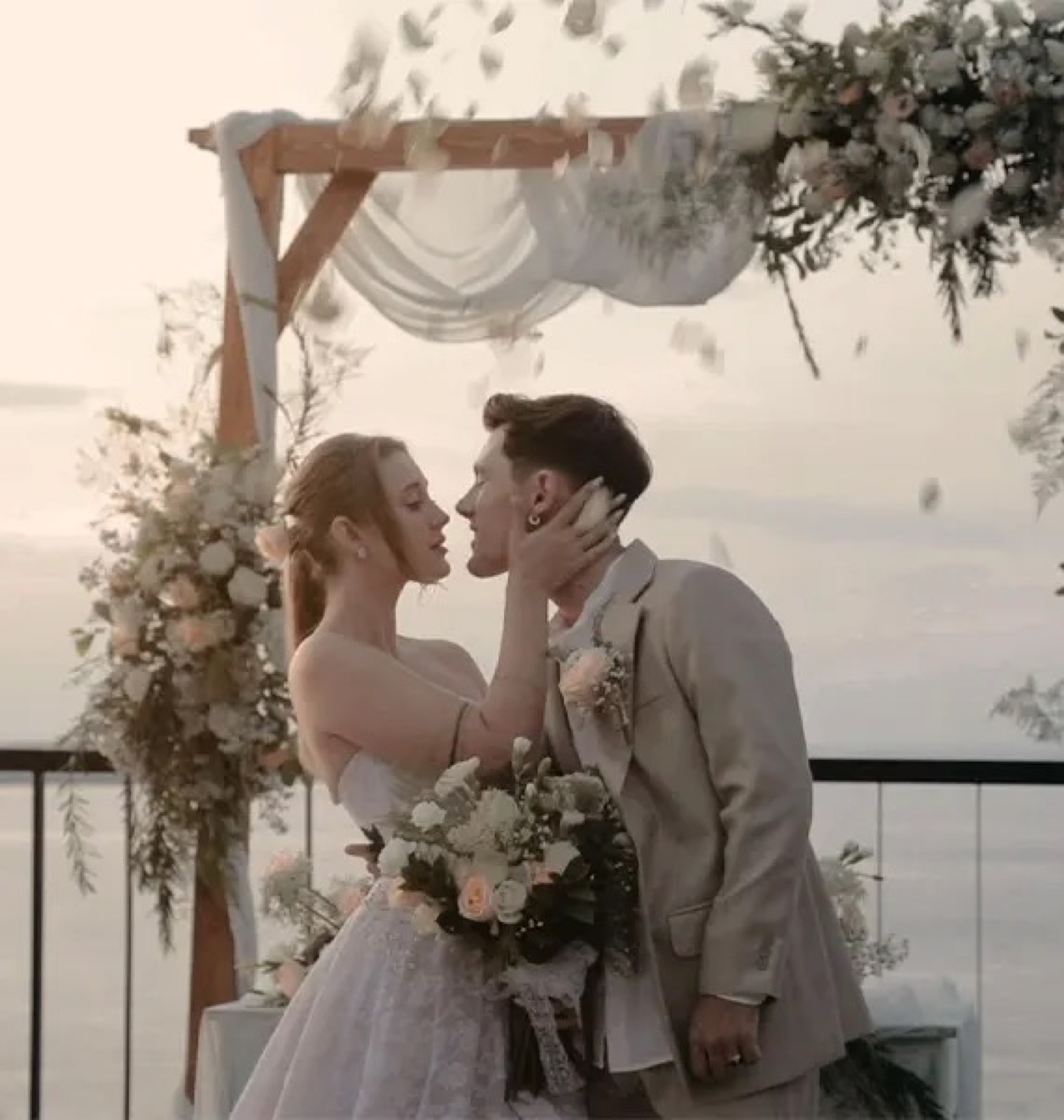 Couple kissing under a draped wedding arch above the sea at Adiwana Warnakali, Nusa Penida, Bali