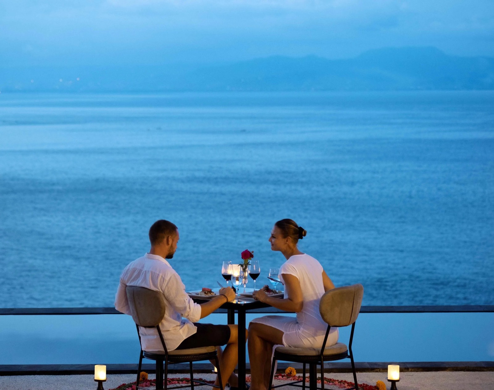 Candlelit dinner for two by the infinity pool at dusk at Adiwana Warnakali on Nusa Penida, Bali