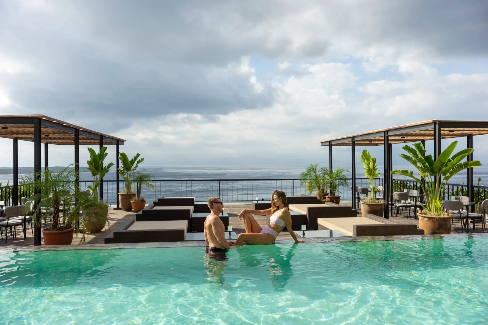 Couple in the rooftop infinity pool overlooking the Toyapakeh strait at Adiwana Warnakali, Nusa Penida, Bali