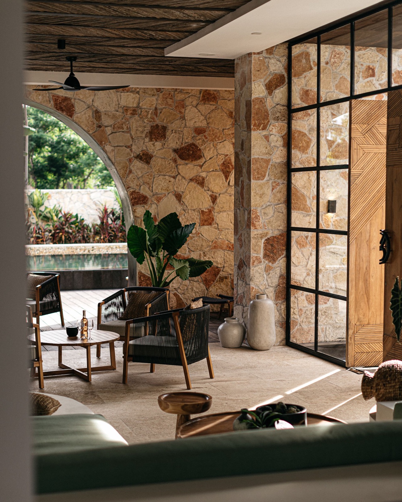 Open lounge with a stone arch and rattan furniture at Alamayah, Sumba