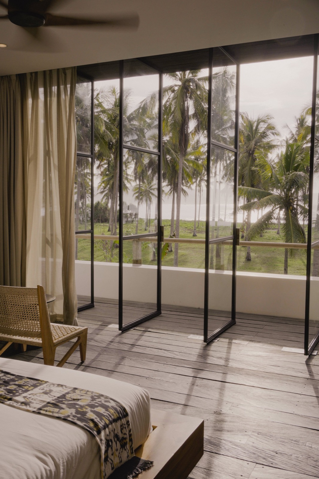 Guest suite with glazed doors looking out to the palms and the ocean at Alamayah, Sumba