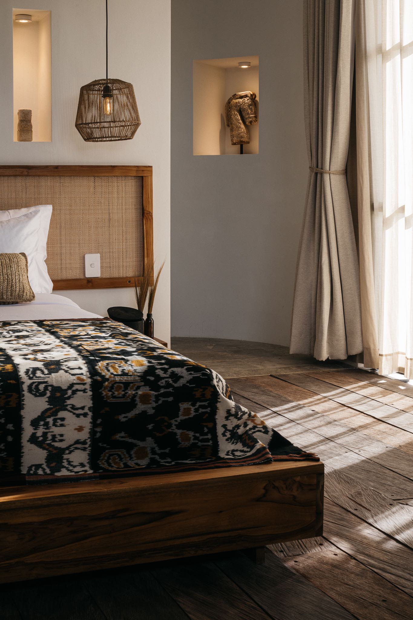 Bedroom with an ikat throw and woven bedhead at Alamayah, Sumba