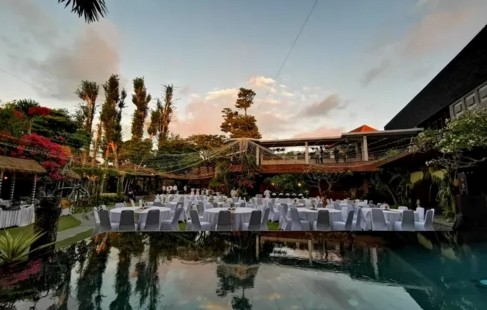 Long banquet tables set beside the reflecting pool in Alindra Villa's courtyard garden at dusk
