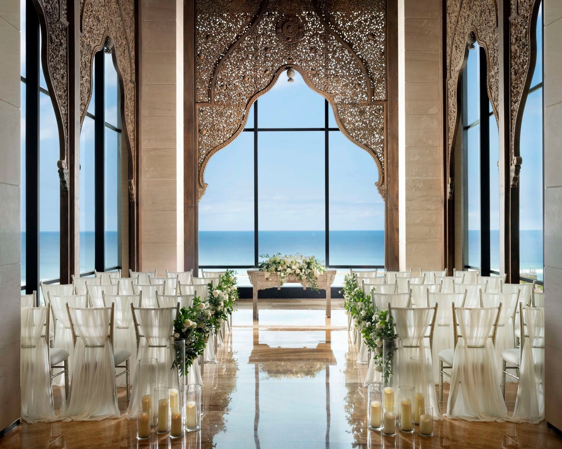 Ocean-view cliff chapel styled with white and green florals and candles down the aisle, The Apurva Kempinski Bali, Nusa Dua