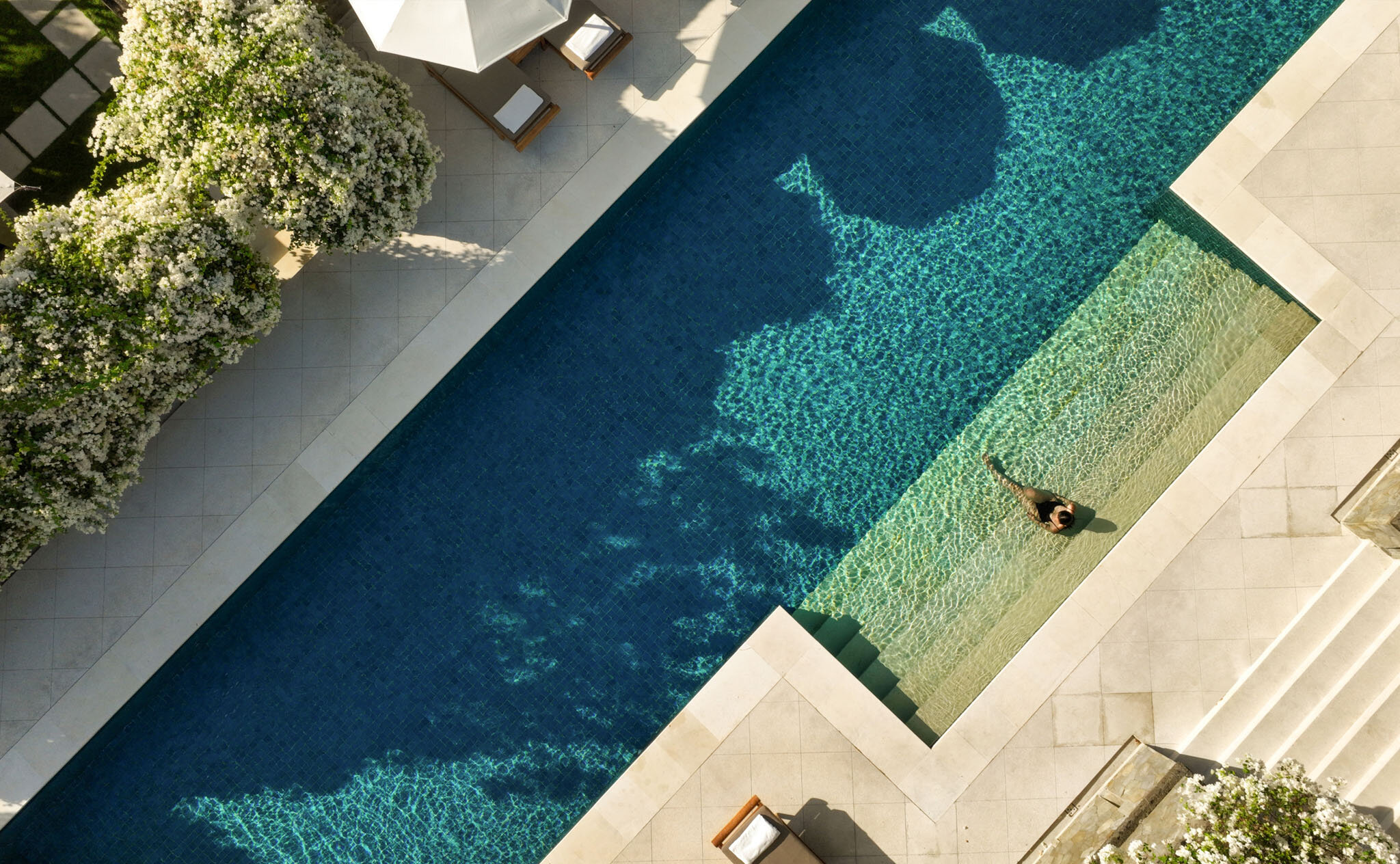 Aerial view of a lap pool with sun loungers and manicured gardens at Aman Villas at Nusa Dua