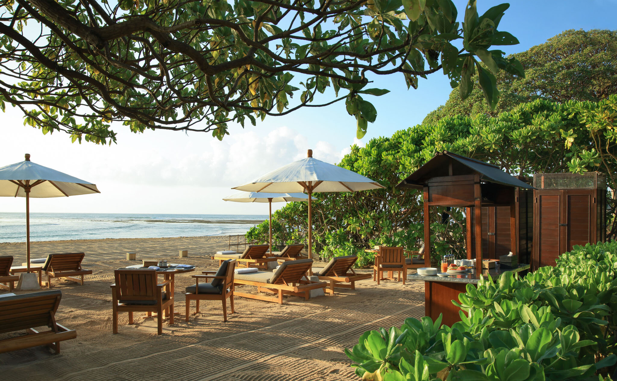 Beach club with wooden loungers, white umbrellas and ocean views at Aman Villas at Nusa Dua, Bali