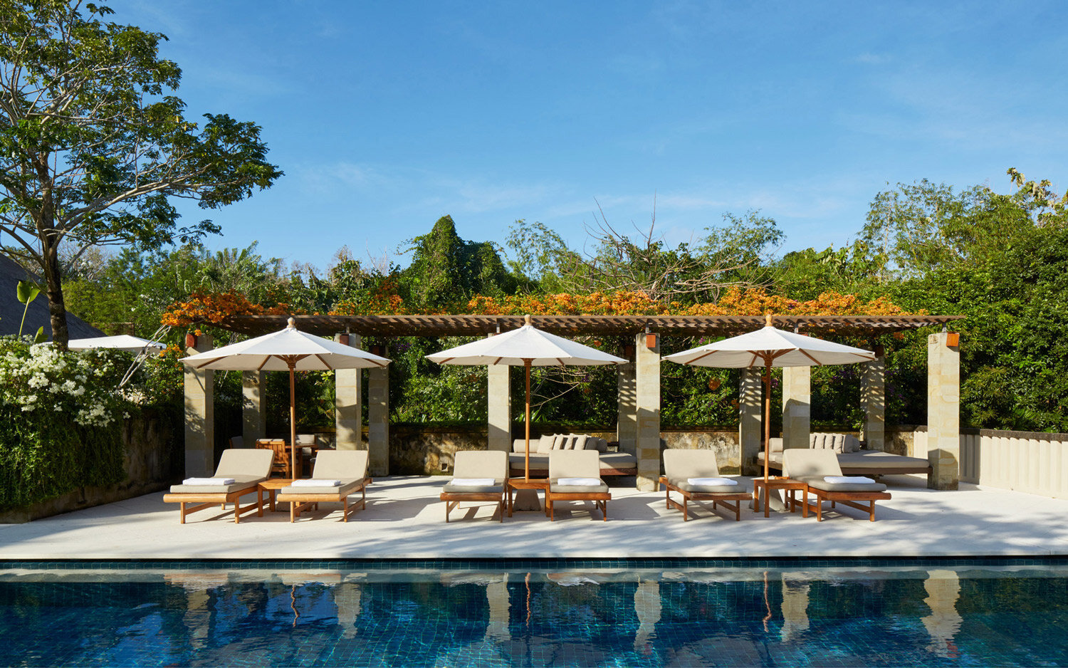 Poolside cabanas with canvas umbrellas and tropical landscaping at Aman Villas at Nusa Dua