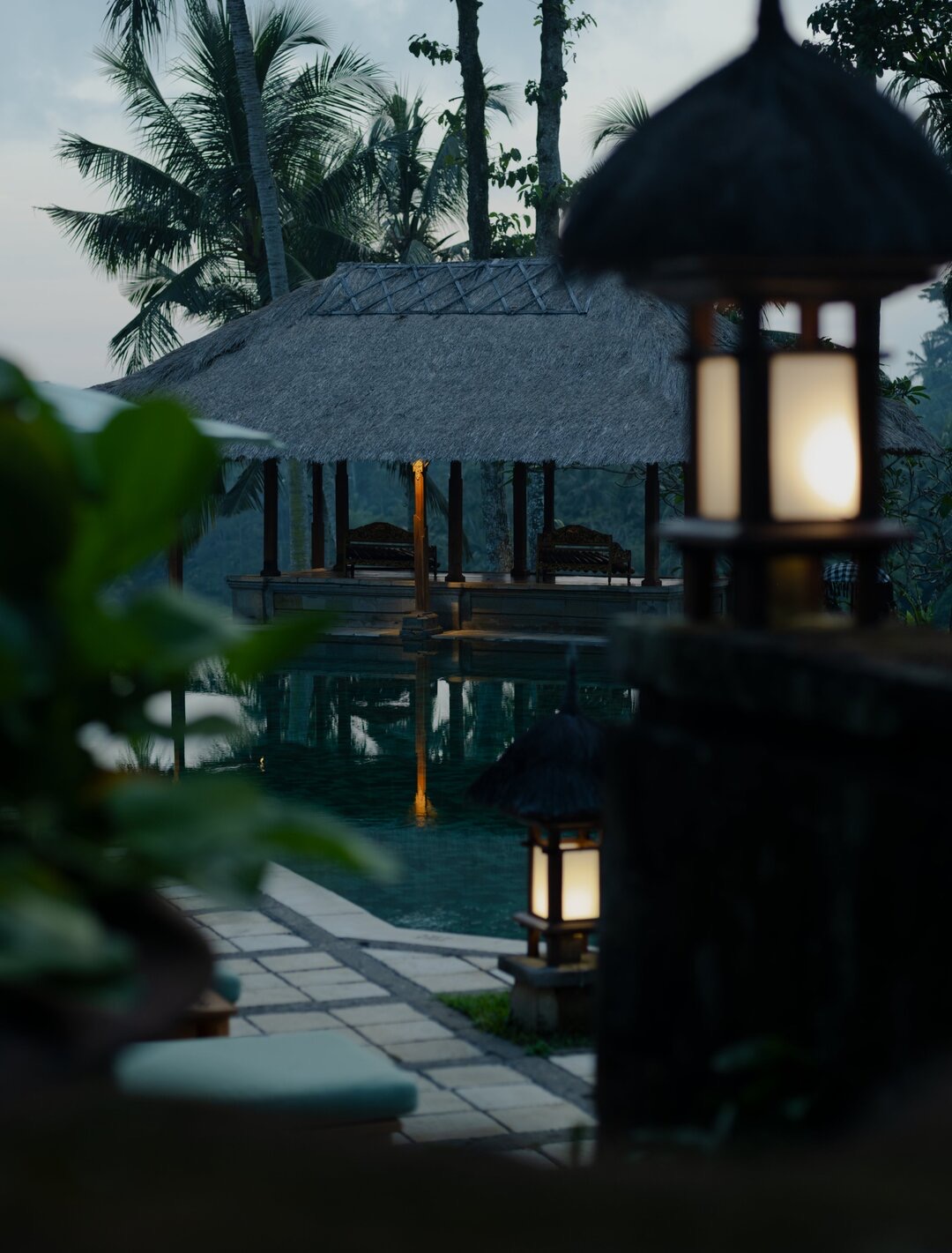 Thatched pavilion lit at evening with water reflection, ceremony space at Amandari, Ubud