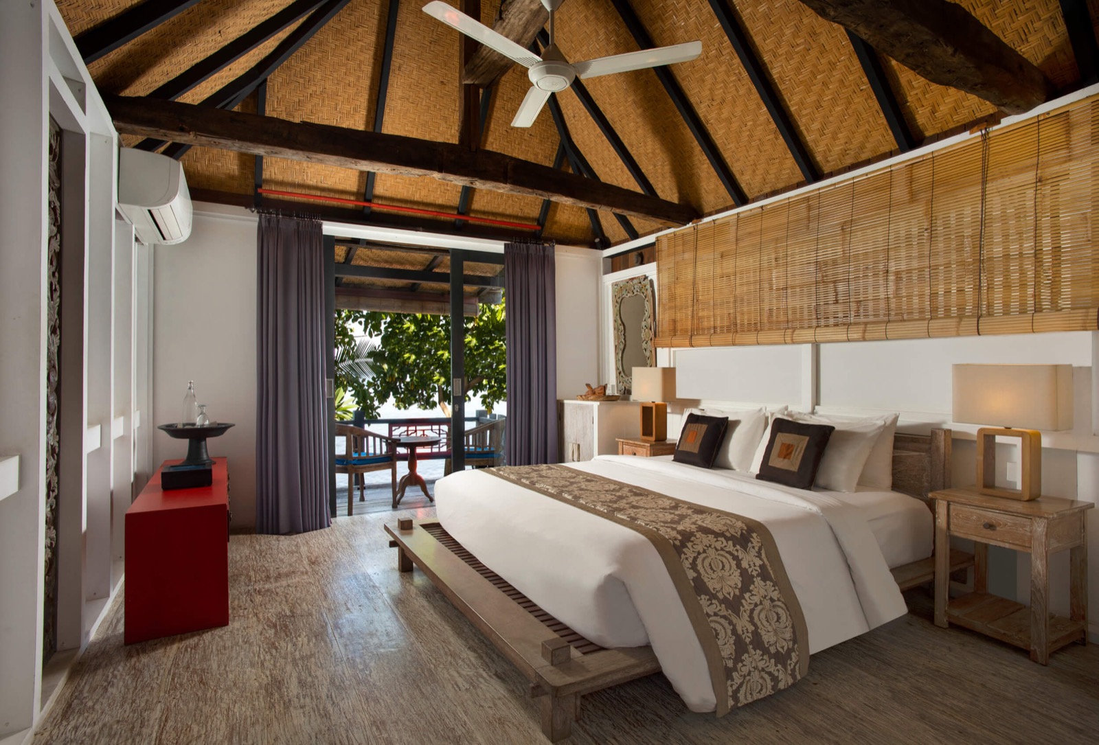 Bedroom under a pitched bamboo roof opening onto a shaded terrace at Amed Lodge by Sudamala Resorts in Amed, east Bali