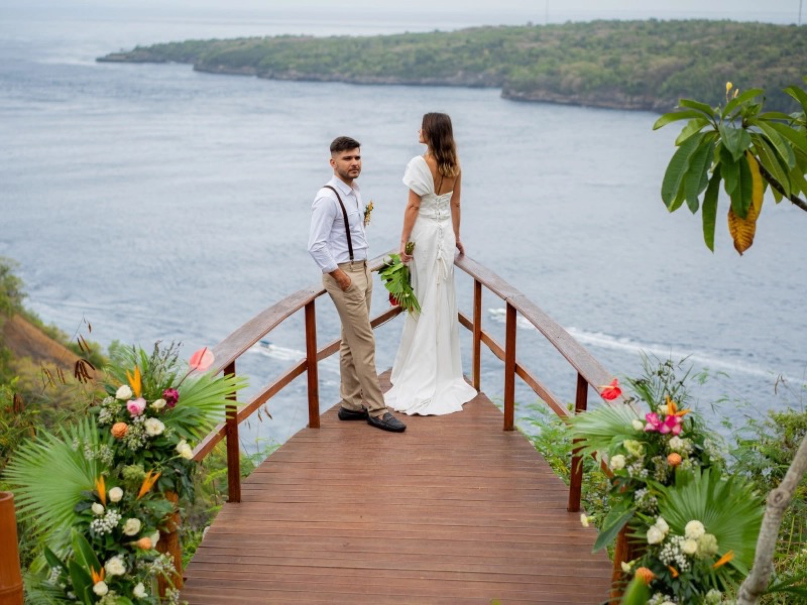 Bride and groom on the wooden viewing deck above the strait at Amok Sunset, Nusa Penida, Bali