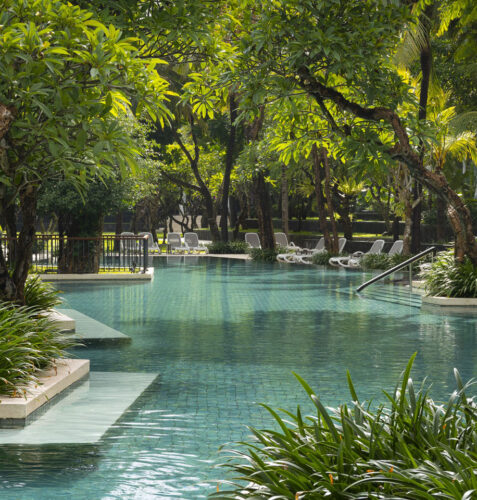 Pool area with palm trees and beachfront view at The Anvaya Beach Resort Bali, Seminyak