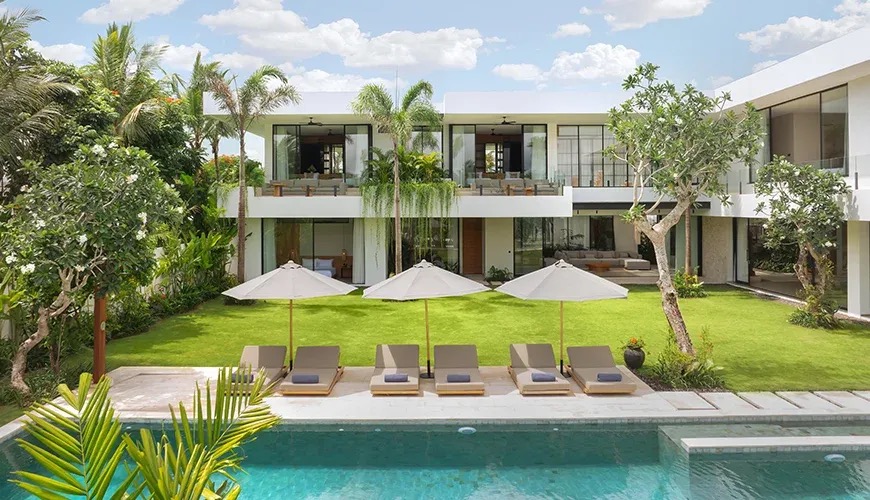 Modern villa with a large pool and loungers at dusk at Arita Villa, Canggu