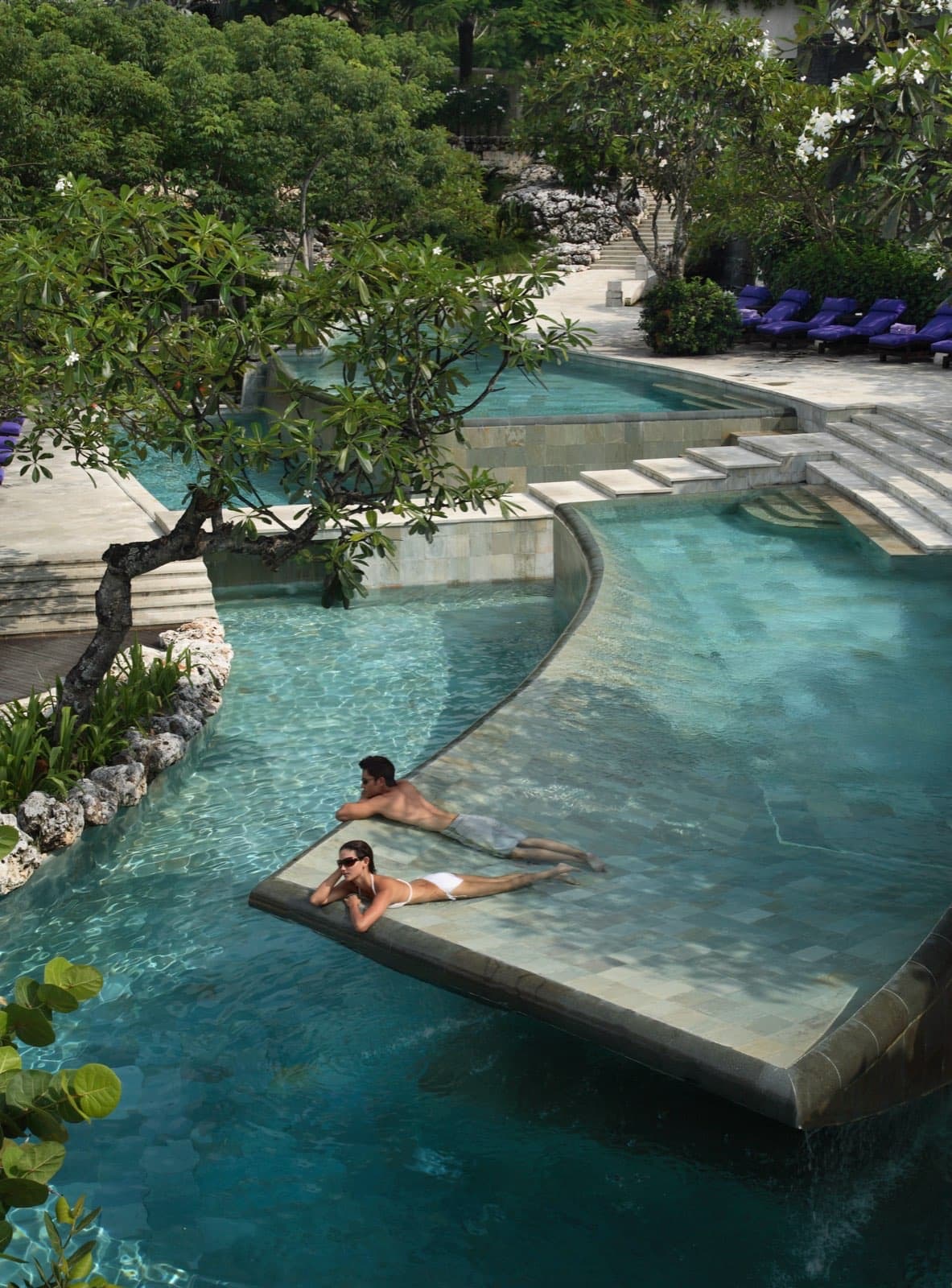 A couple by the ocean-view river pool at AYANA Resort Bali on the Jimbaran clifftop