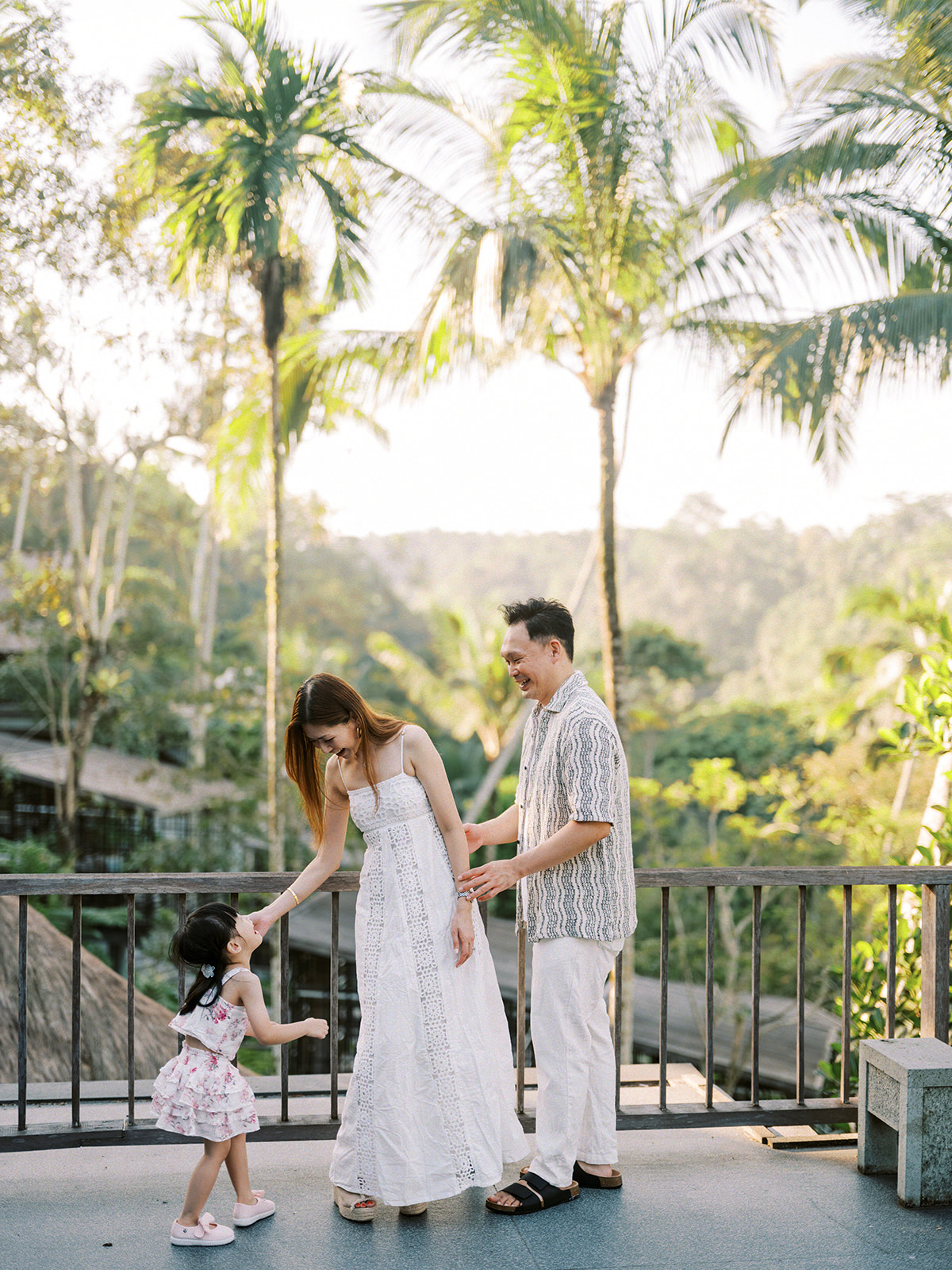 Couple with child on the resort deck, framed by palm trees and valley views, Ayung Resort Ubud, Payangan