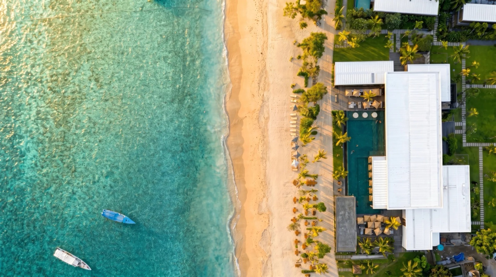 Overhead view of the reef, empty white sand and moored outrigger boats in front of BASK Gili Meno, Gili Meno