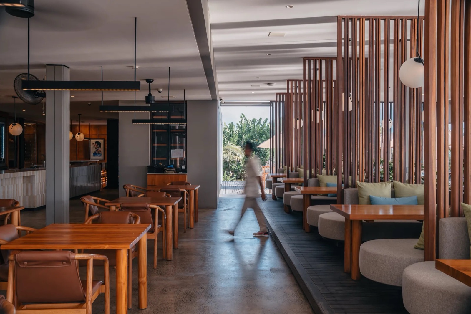 Restaurant interior with timber screens, banquettes and teak tables at BASK Gili Meno, Gili Meno
