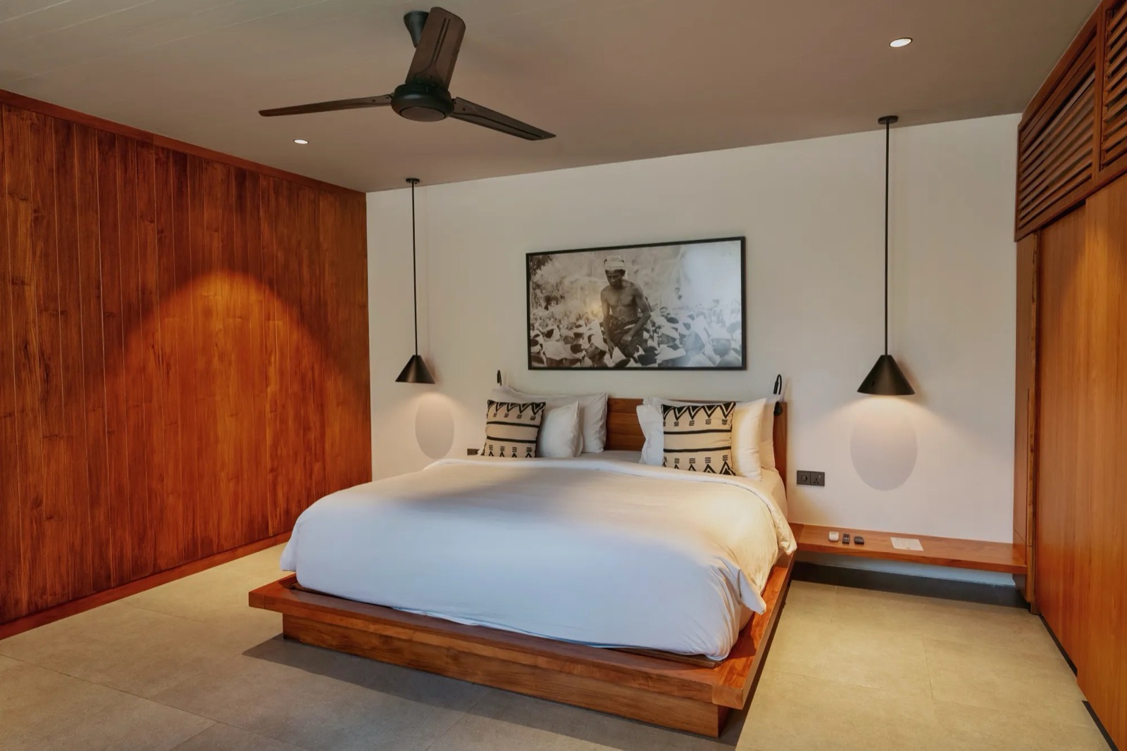 Suite bedroom with a timber-panelled wall and pendant lights at BASK Gili Meno, Gili Meno