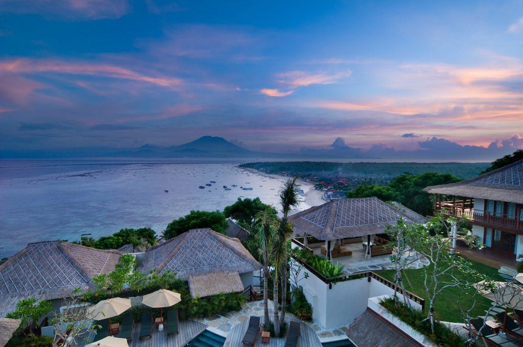 Aerial view at dusk over the thatched roofs of Batu Karang Lembongan Resort & Spa and the bay at Jungut Batu, Nusa Lembongan, Bali