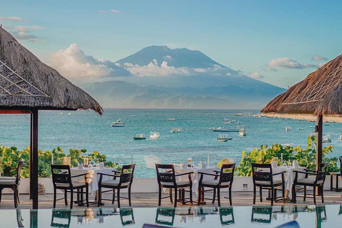 Ocean-view dining terrace at Muntigs restaurant with Mount Agung across the water, Batu Karang, Nusa Lembongan, Bali