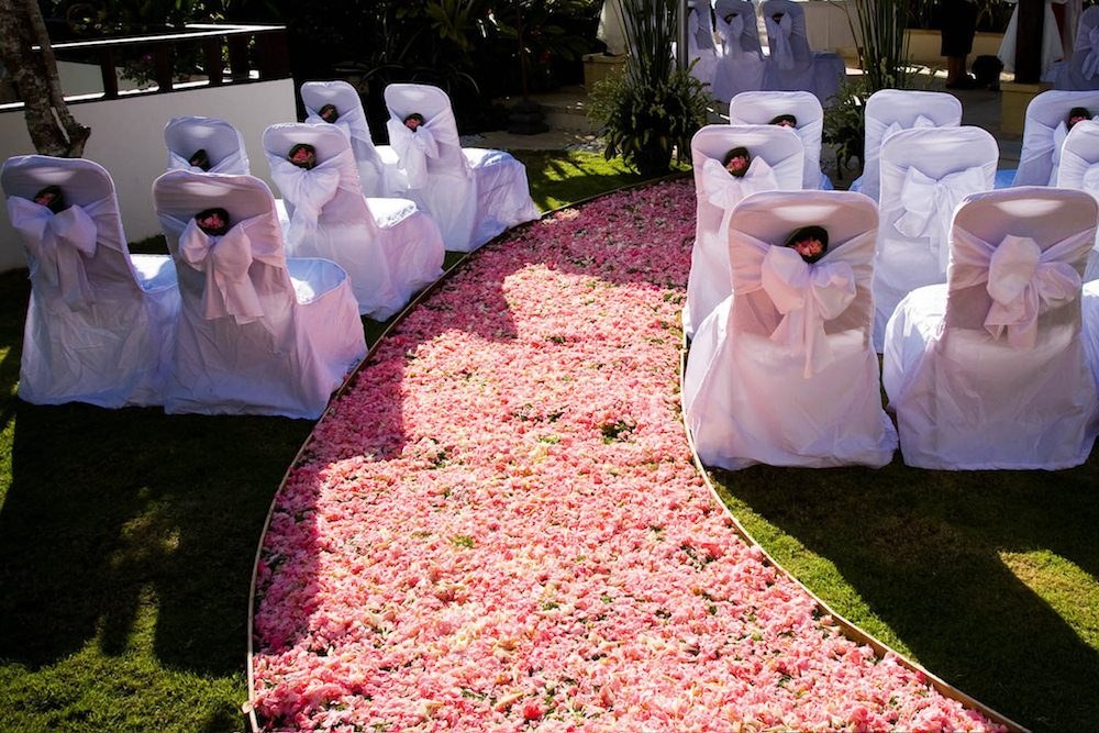 Wedding ceremony set with white chair covers and a petal aisle on the event lawn at Batu Karang Lembongan Resort & Spa, Nusa Lembongan, Bali