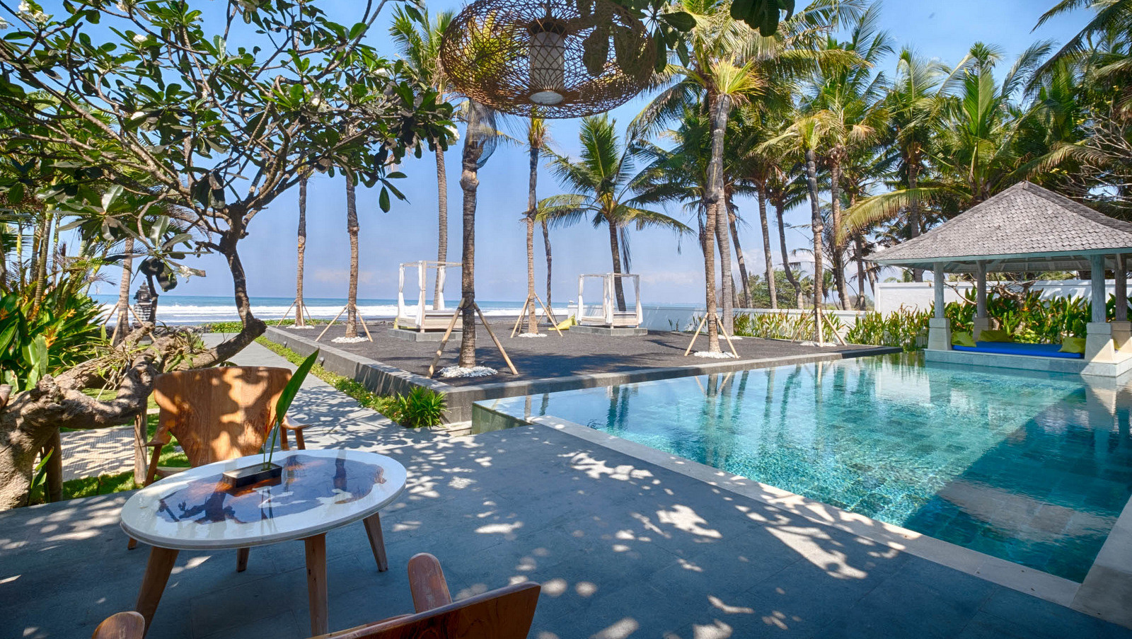 The beachfront pool and garden pavilion at Biara Villa on Saba Beach, Ketewel, with ocean views and tropical palms