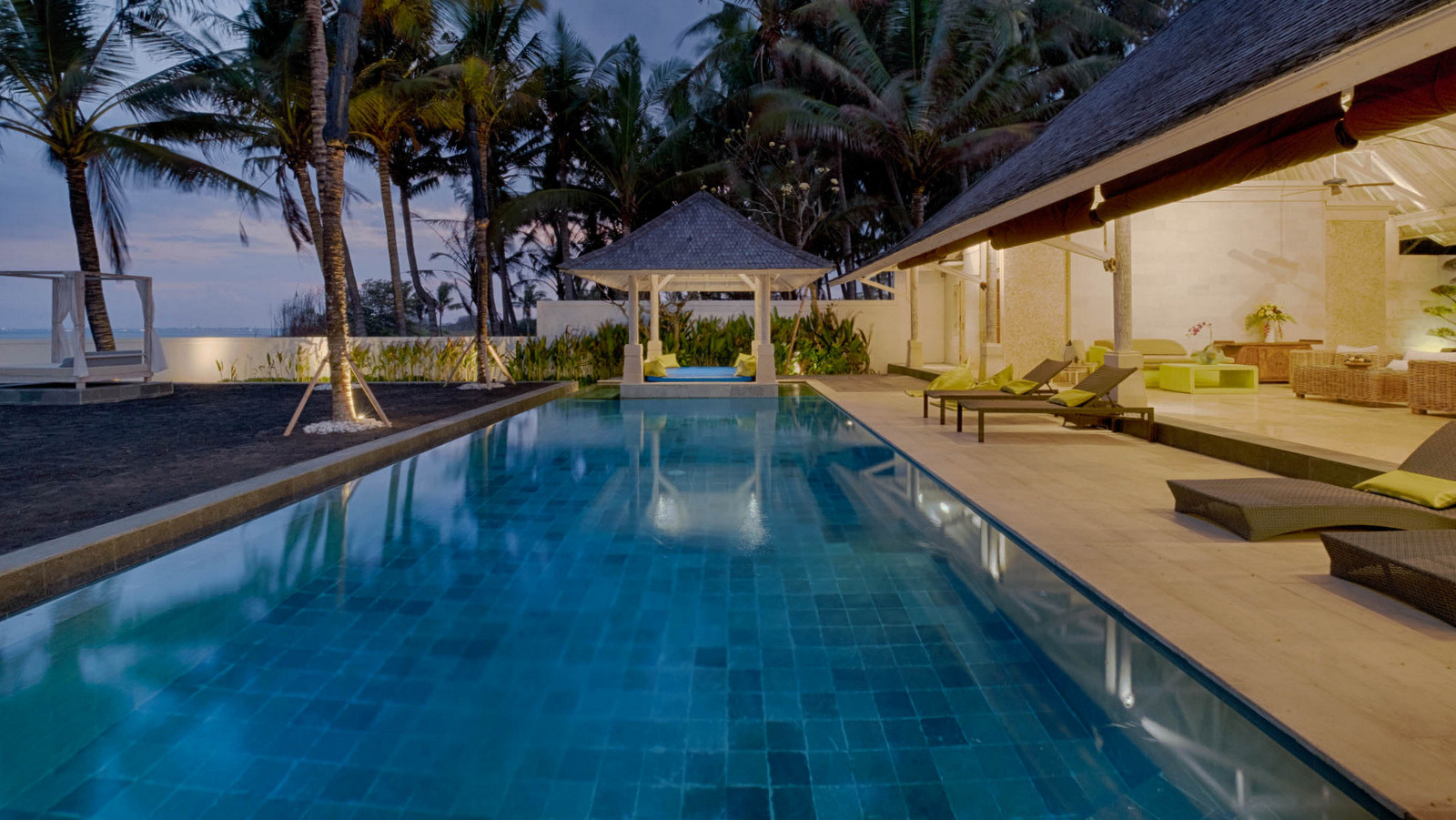 Evening view of the infinity pool and covered pavilion at Biara Villa with ocean views beyond