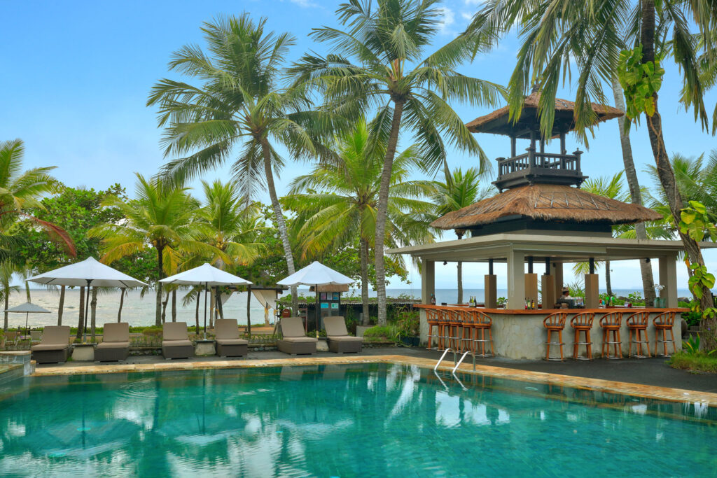 Ombak Bar and pool deck at Candi Beach Resort with palm trees and ocean backdrop