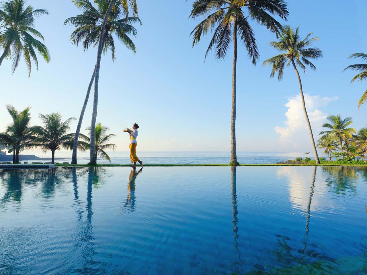 Infinity pool at Candi Beach Resort overlooking Mendira Beach with palm trees framing the sea