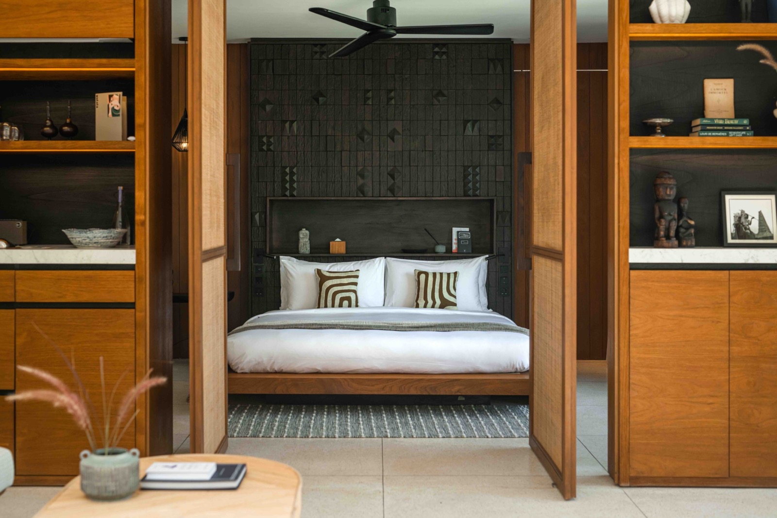 Guest suite with carved timber screens and a Sumbanese-patterned headboard at Cap Karoso, Sumba