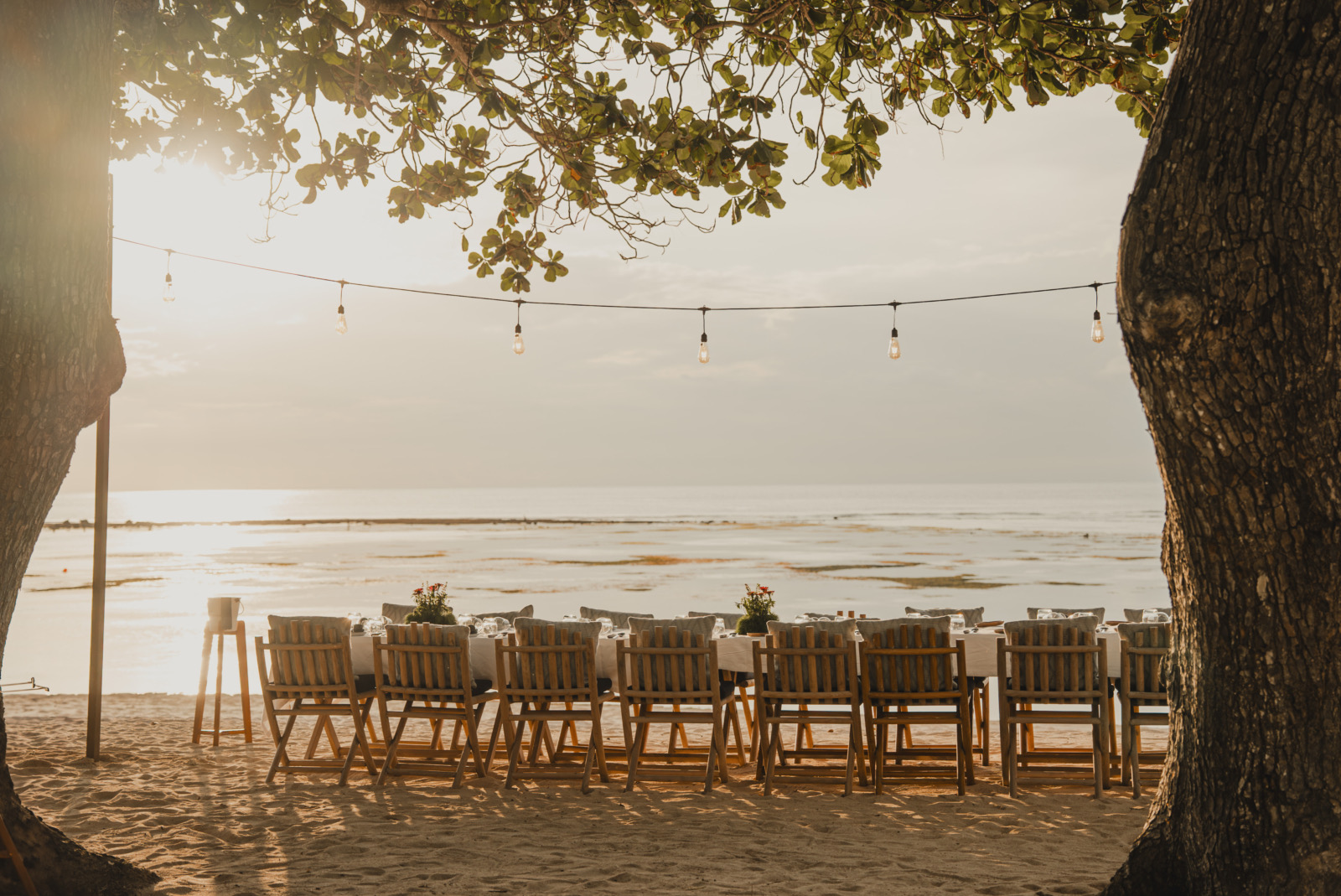 Long dinner table set on the sand under festoon lights at golden hour at Cap Karoso on Sumba, one flight from Bali