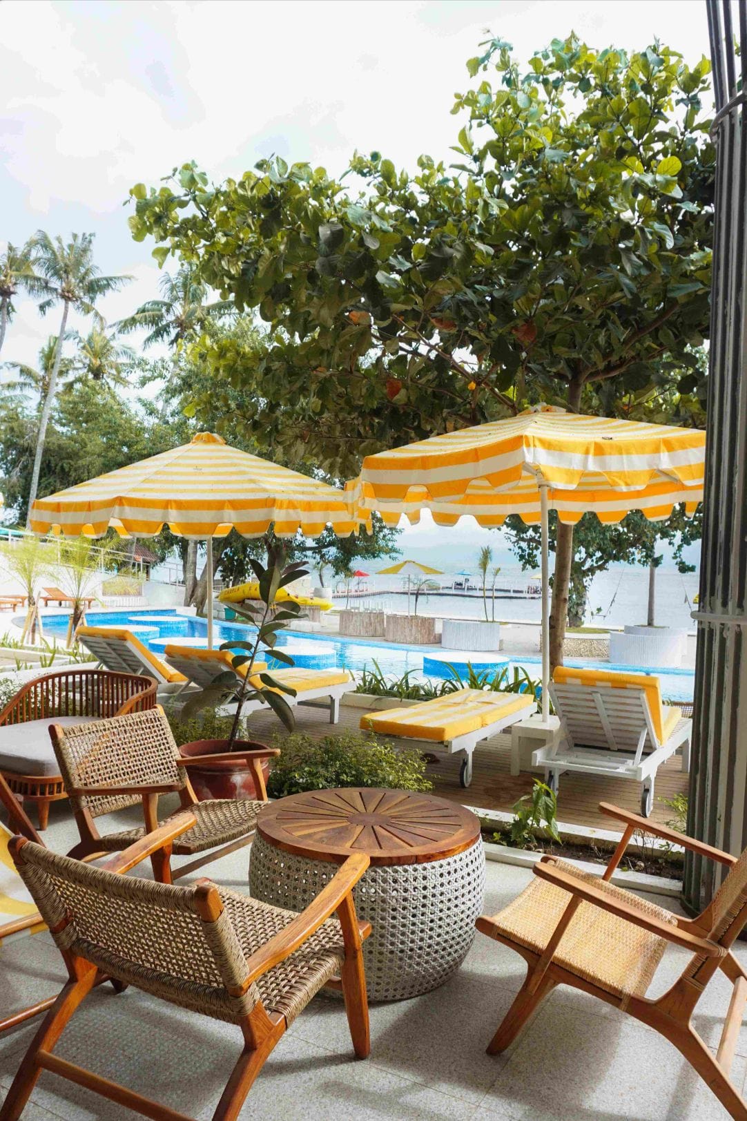 Rattan lounge chairs beside the pool and sunbeds at Caspla Beach Club Nusa Penida, Bali