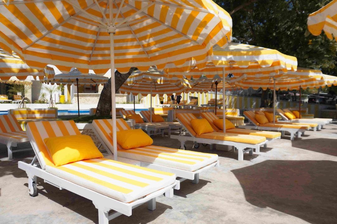 Striped sunbeds and parasols on the pool deck at Caspla Beach Club Nusa Penida, Bali