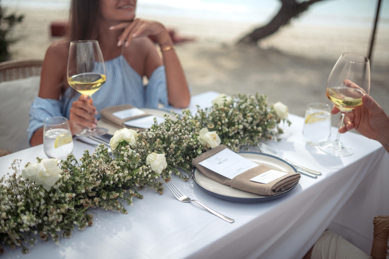 Beachside table set with a long white floral runner and menu cards at Cocana Resort, Gili Trawangan