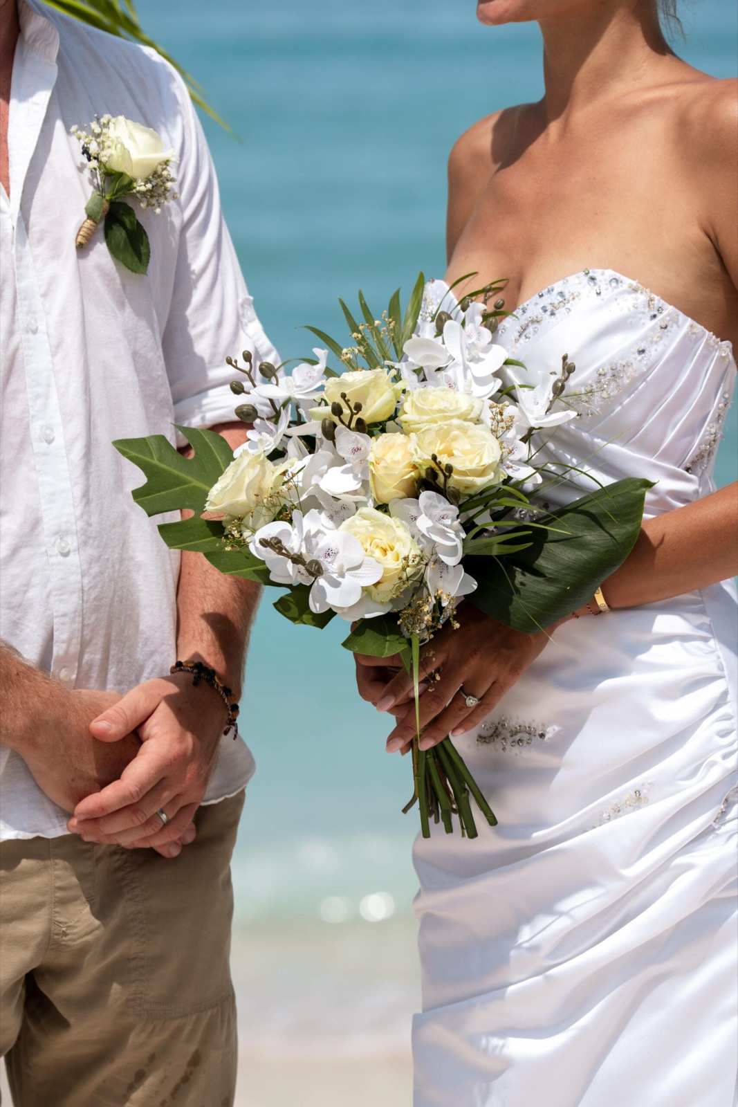 Bride holding a white rose and orchid bouquet beside the groom on the sand at Cocana Resort, Gili Trawangan
