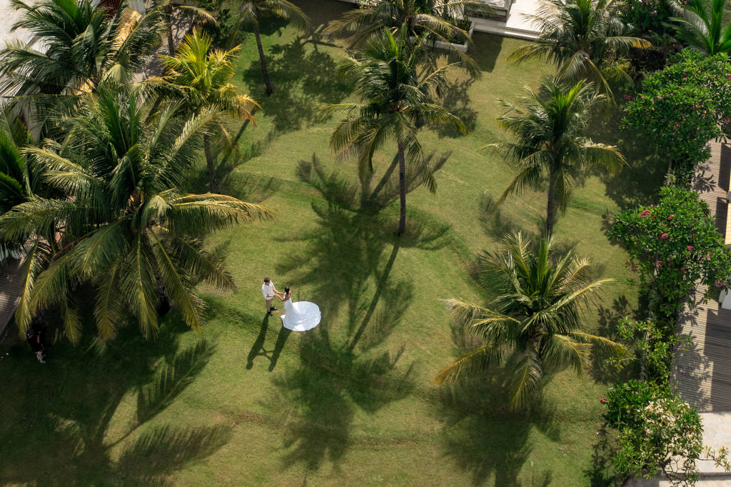 Aerial view of a couple on the palm-shaded lawn between the villas at Cocana Resort, Gili Trawangan