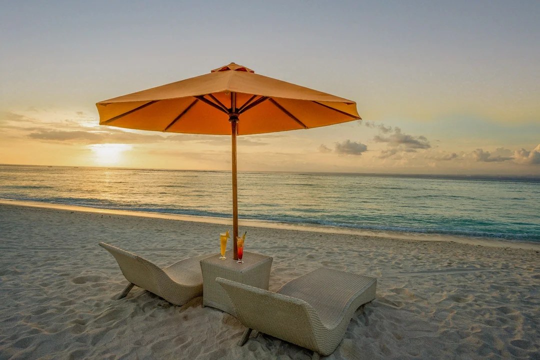 Sun loungers and an umbrella on the sand at sunset at d'Nusa Beach Club and Resort, Nusa Lembongan, Bali