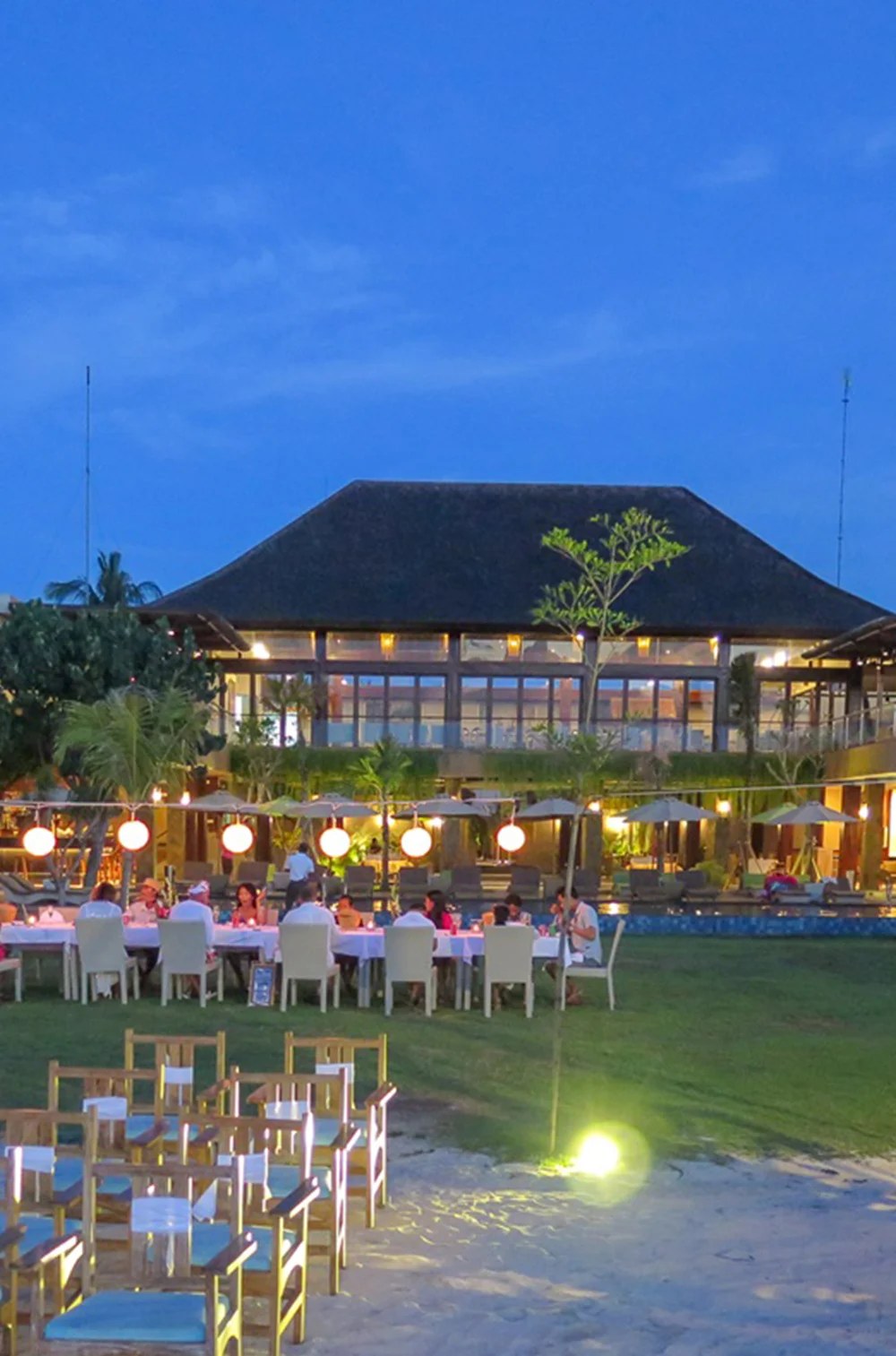 Reception tables set on the lawn in front of the restaurant at dusk at d'Nusa Beach Club and Resort, Nusa Lembongan, Bali