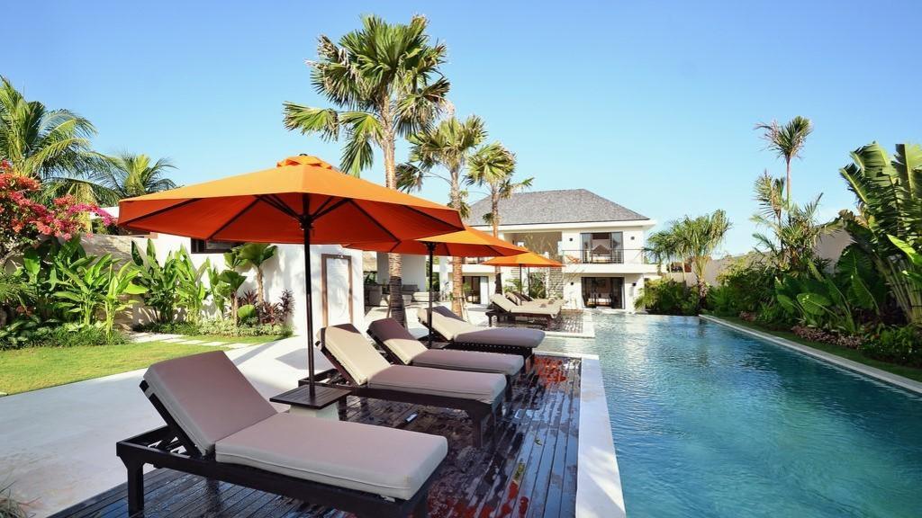 Sun loungers under orange umbrellas beside the 20-metre lap pool at Echo Beach Duo Villa Enam