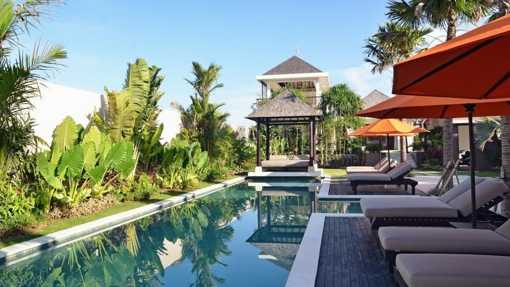 The lap pool, garden, and gazebo at Echo Beach Duo Villa Enam in daylight