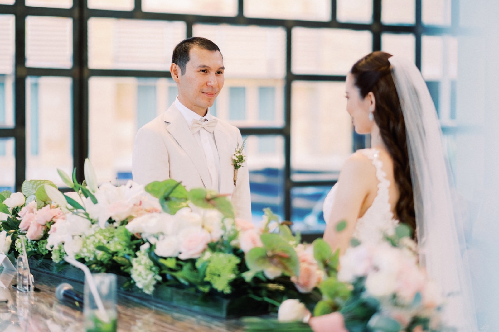 Bride and groom at the altar of Eternity Chapel with the lake and glass walls behind, The Mulia, Nusa Dua