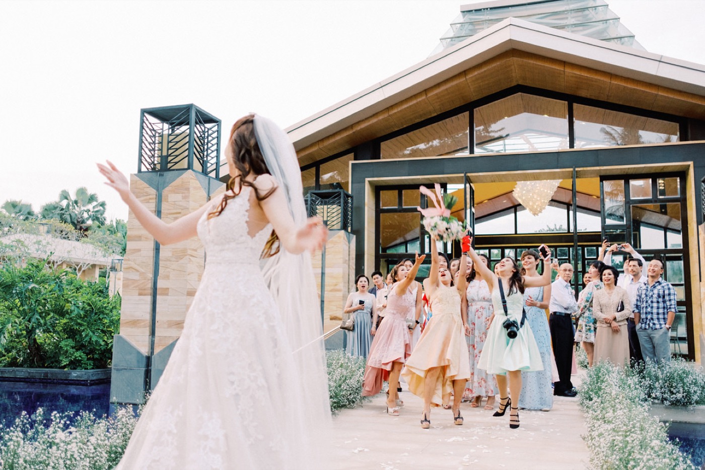 Guests gathered by the glass Eternity Chapel over the water at The Mulia, Nusa Dua