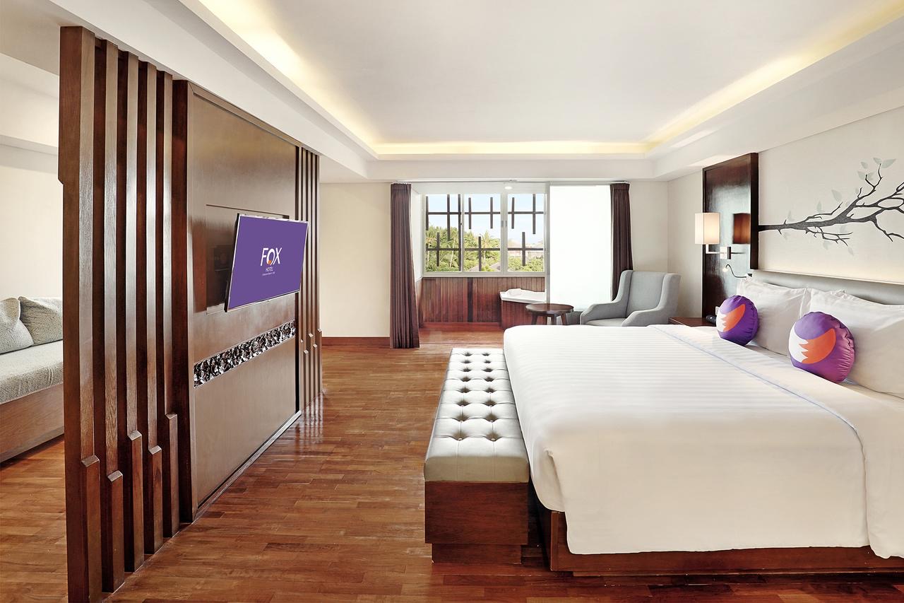 A spacious guest room at FOX Hotel Jimbaran Beach with warm timber floors and garden view