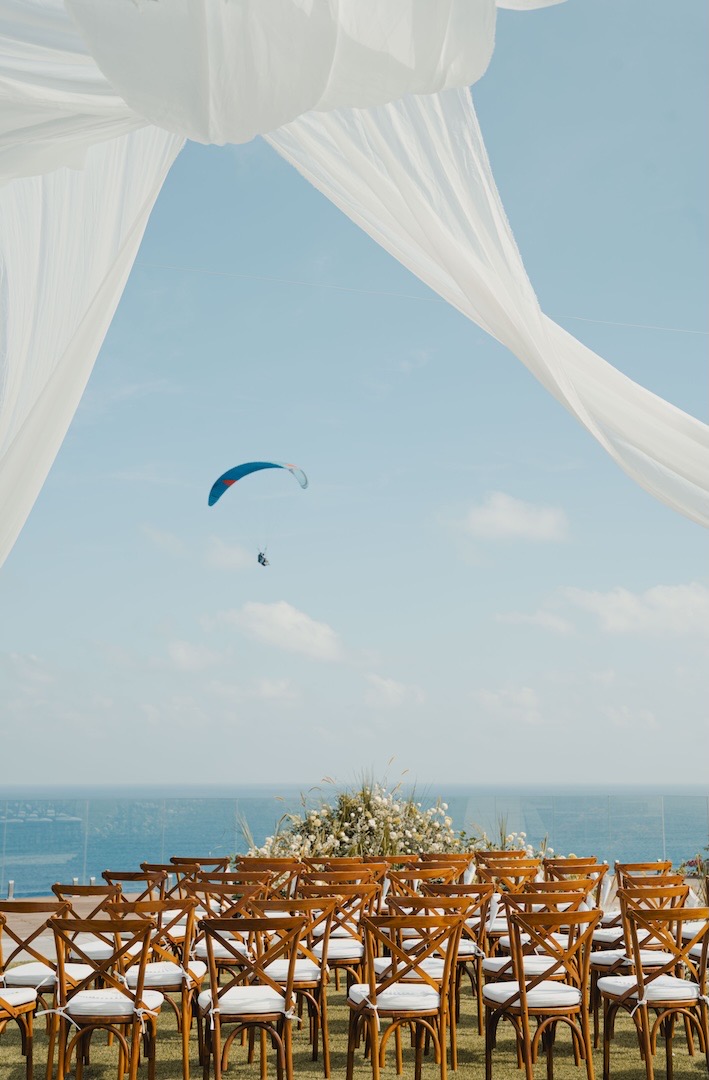 Ceremony seating with white drapes framing the sea view at clifftop Glamp Nusa, Nusa Dua