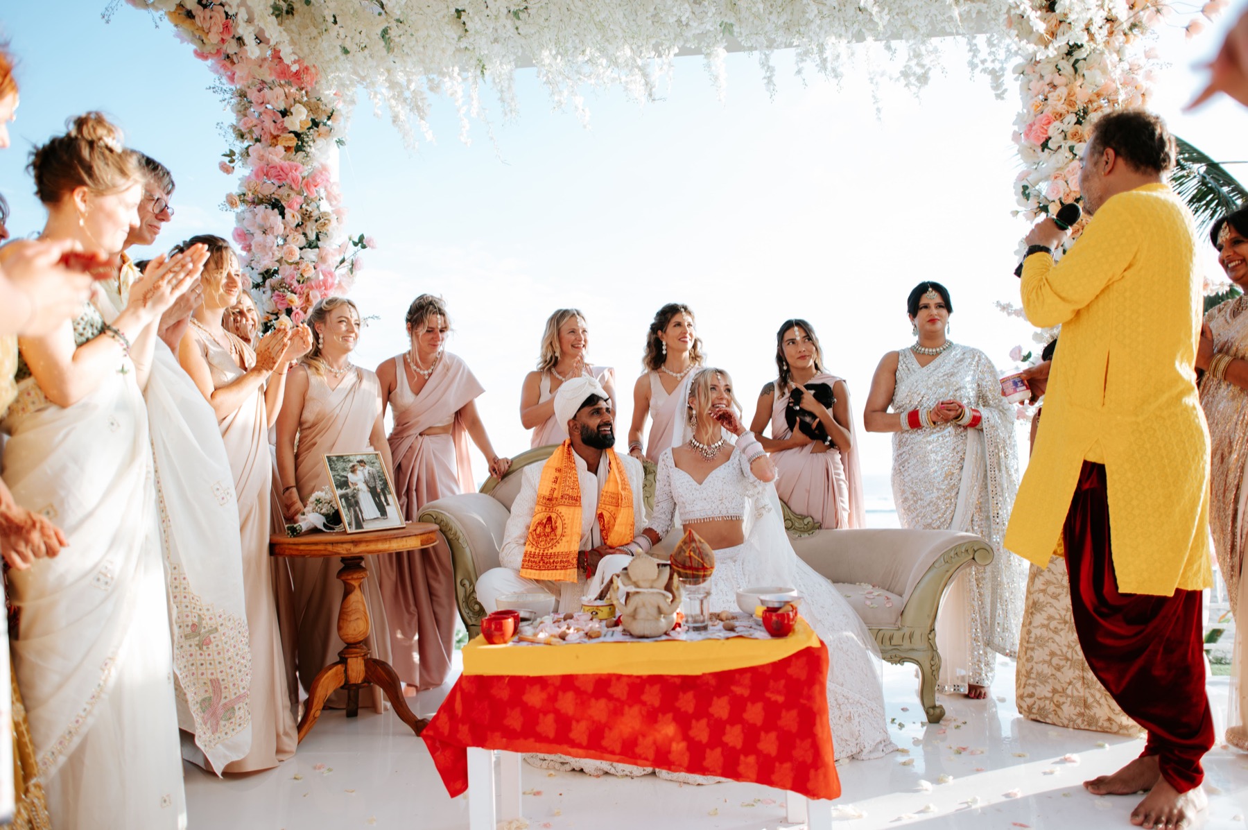 A large floral-arch wedding ceremony with guests and the ocean behind at Glamp Nusa, Nusa Dua