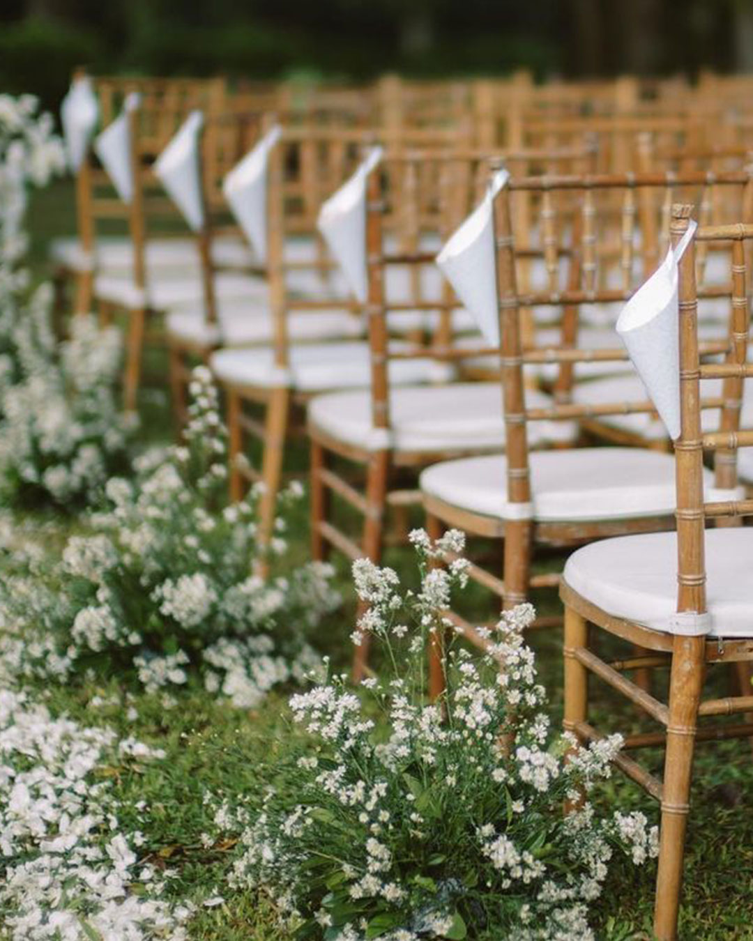 Rows of tiffany chairs with paper cones and a white floral aisle set for a ceremony at Handara Golf & Resort Bali, Pancasari, Bali