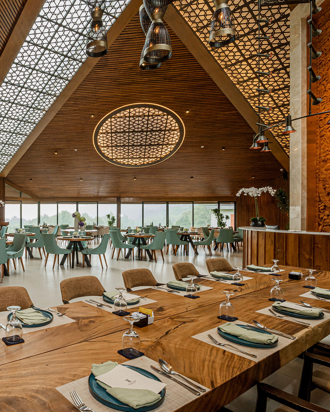 Clubhouse restaurant with a high timber A-frame roof and a long shared table looking out to the misted course at Handara Golf & Resort Bali, Bali