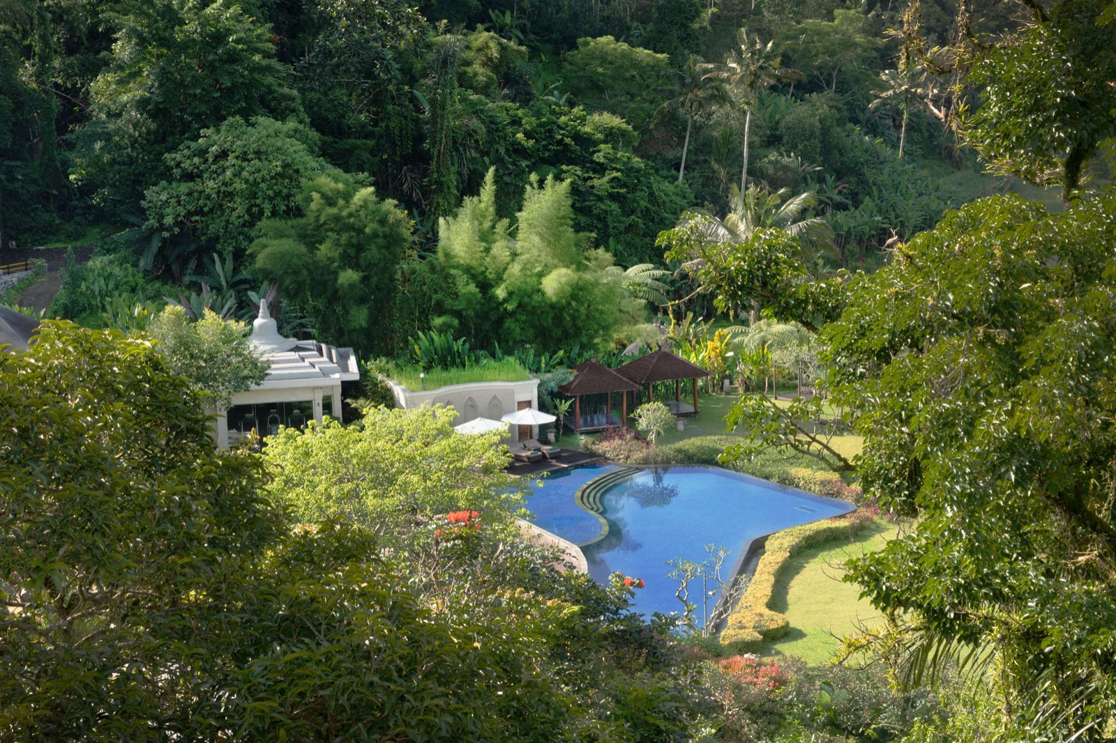 Gardens, thatched pavilions and the swimming pool seen from above through the forest at HOMM Saranam Baturiti, Baturiti, Bali